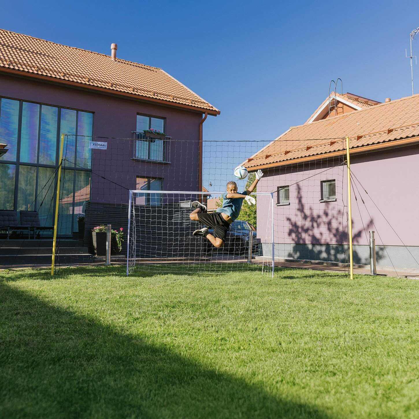 Child practicing soccer save using 3-in-1 Football Goal Trainer in backyard